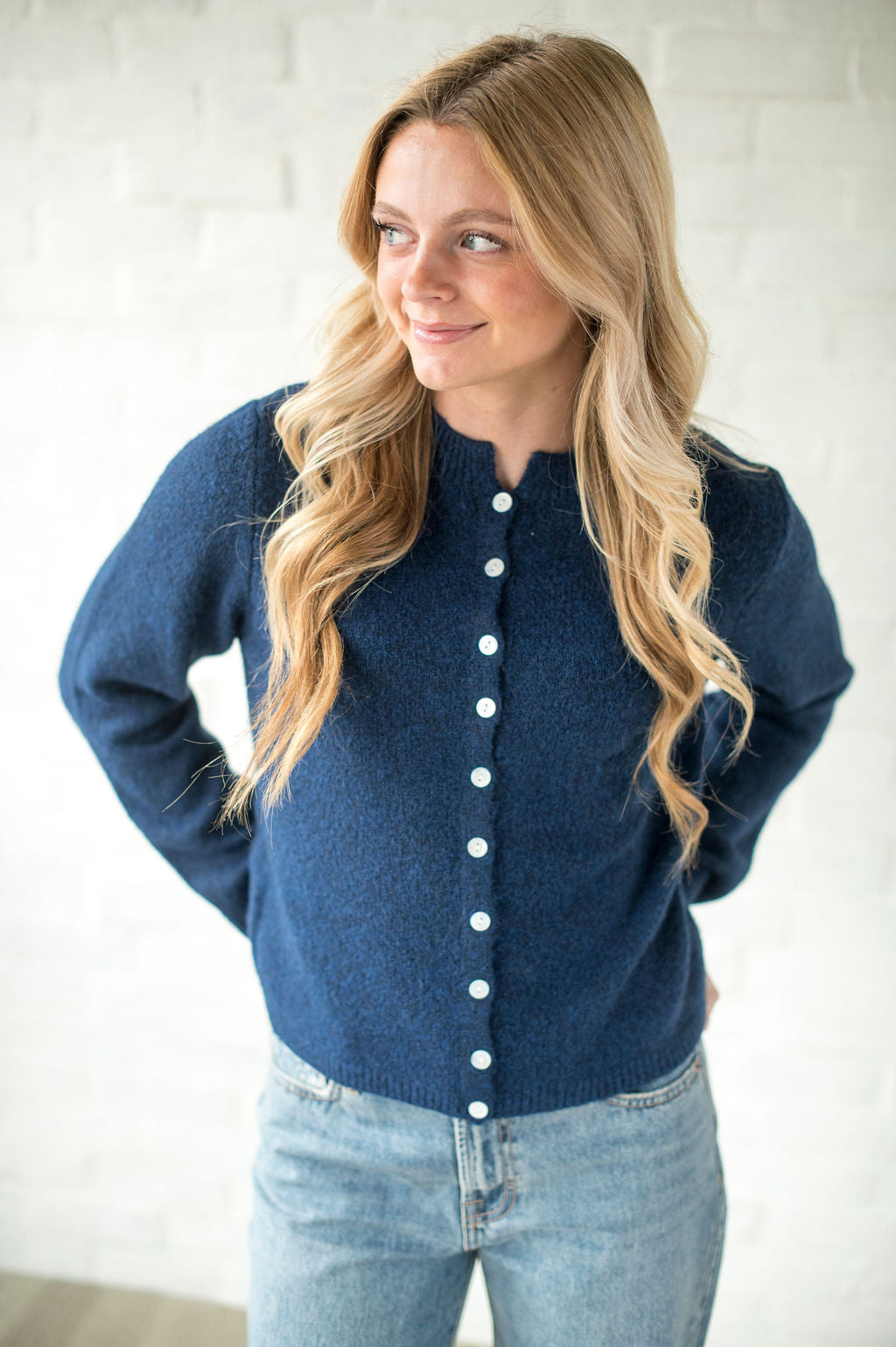 Woman wearing a blue cardigan with white buttons against a white background